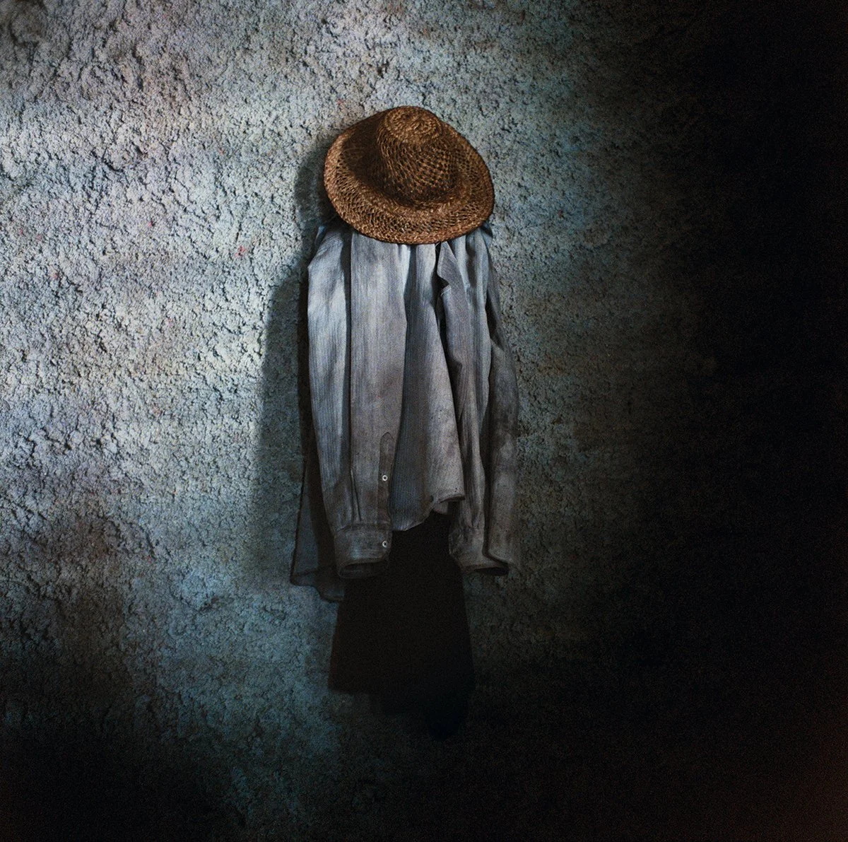 Straw hat on a garment hanging from a stone wall.