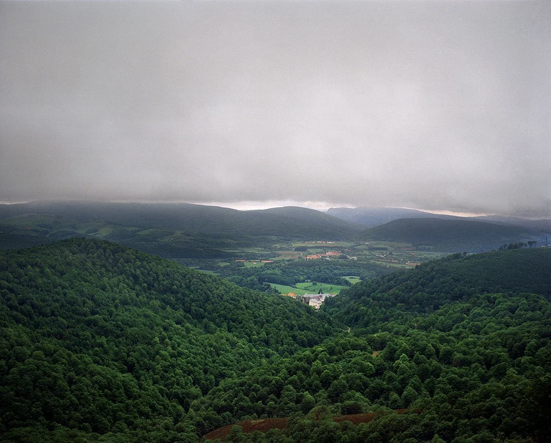 Landscape of a green valley with mountains in the background under a cloudy sky