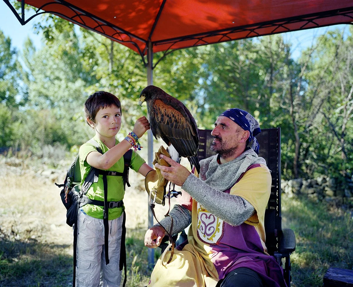A child and a man look at an eagle in an outdoor aviary during an educational activity.