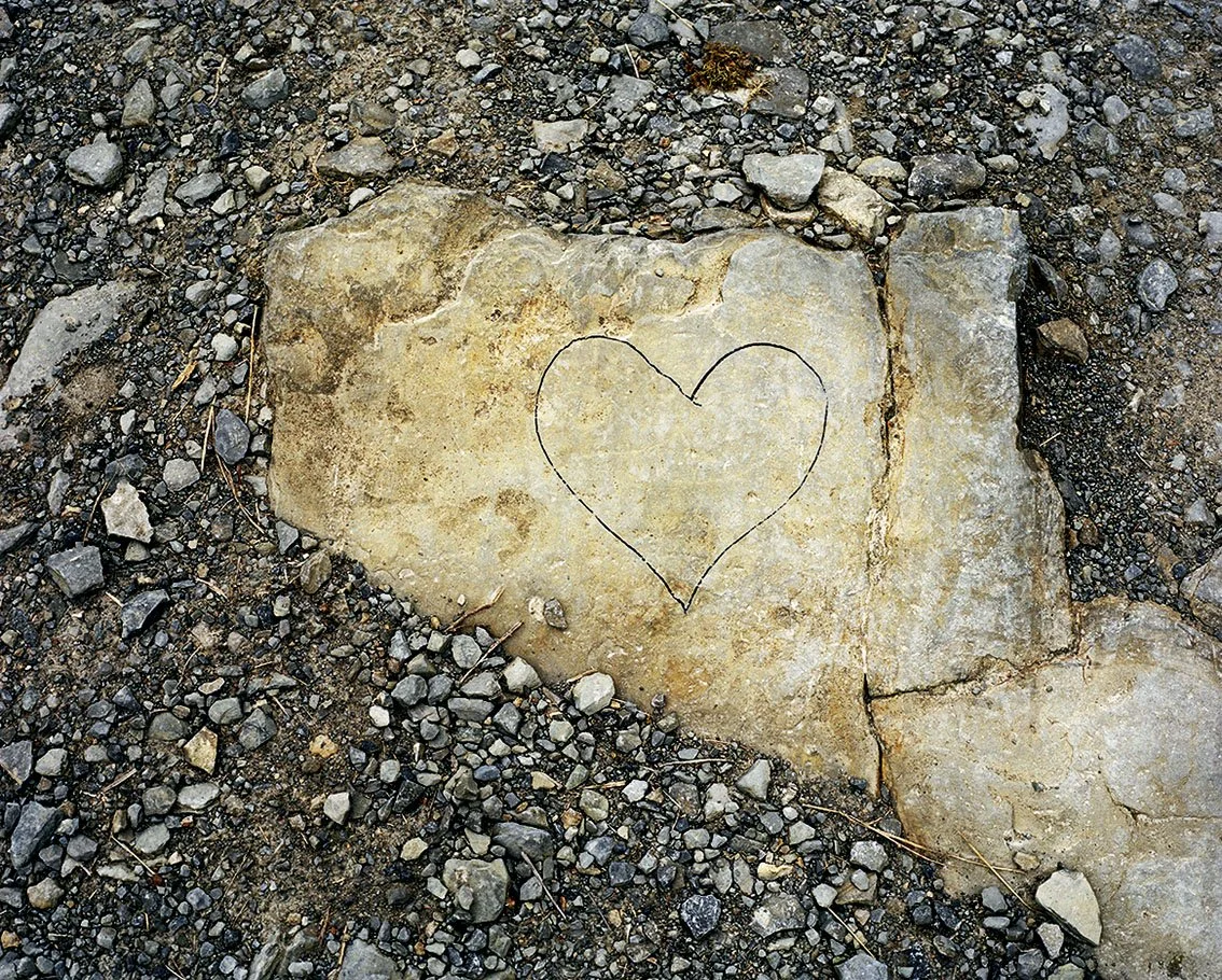 A stone placed on the ground with a heart traced inside.