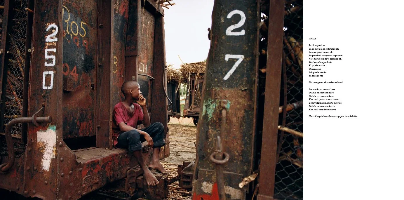 Un jeune garçon assis sur la marche d'une vieille locomotive rouillée, l'air pensif, dans un environnement rustique avec des wagons en arrière-plan.