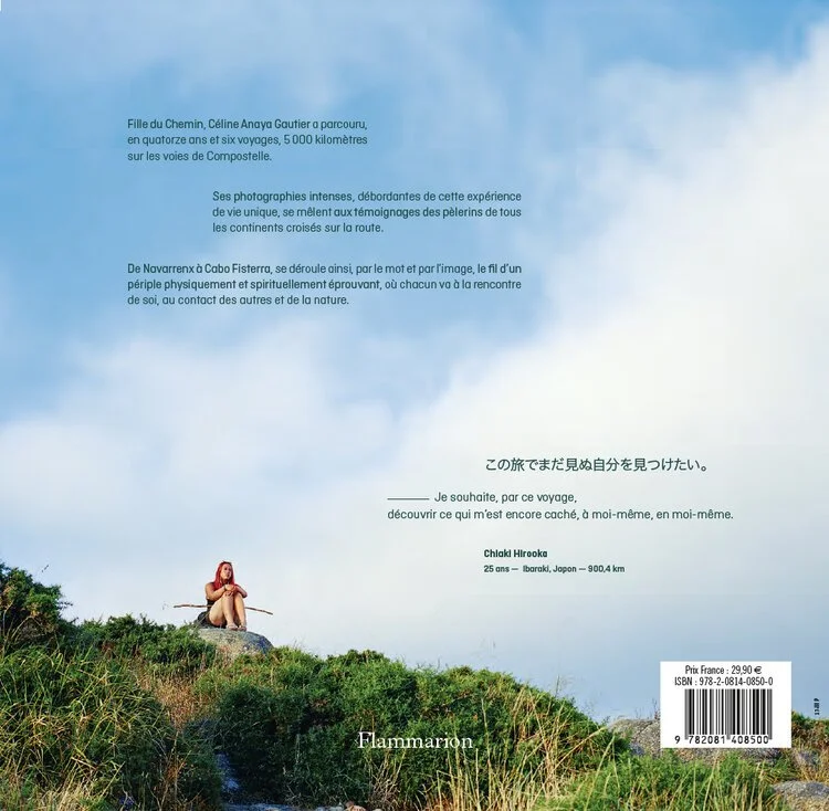 Jeune femme rouge vêtue assise sur un rocher dans la nature, sous un ciel bleu avec des nuages, entourée de végétation, évoquant un voyage de 900 kilomètres de Ibaraki, Japon.