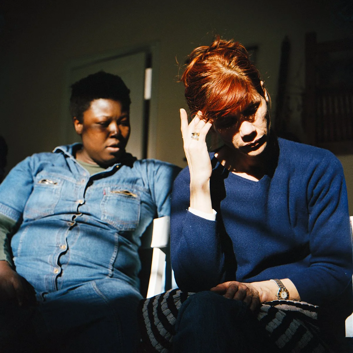 Deux femmes assises, une avec une main à la tête, semble préoccupée ou stressée.
