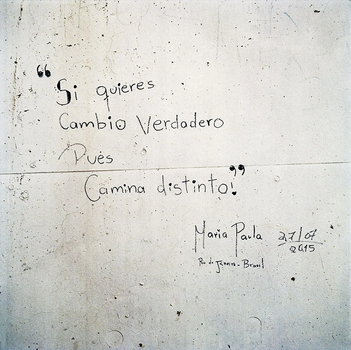 A handwritten inscription on a wall that reads "Si quieres cambio verdadero pues camino distinto!" by Maria Paula, dated 27/01/2015, in Rio de Janeiro, Brazil.