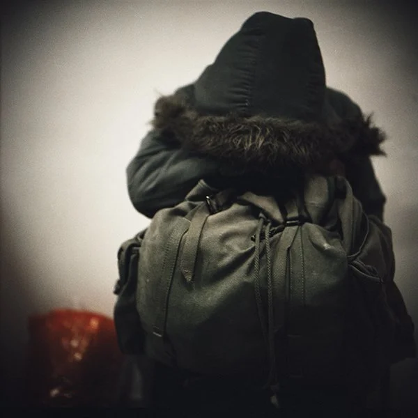 Personne portant un sac à dos et un manteau à capuche dans un intérieur