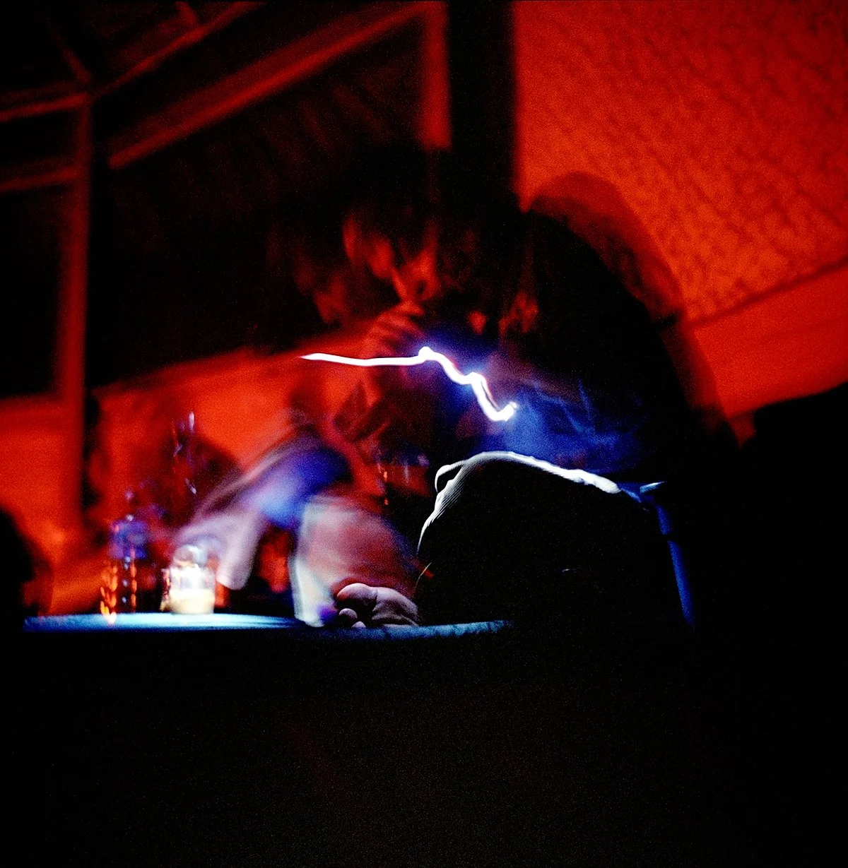 A person using a light source to write or draw in a dark environment, with a red atmosphere and dim lighting.