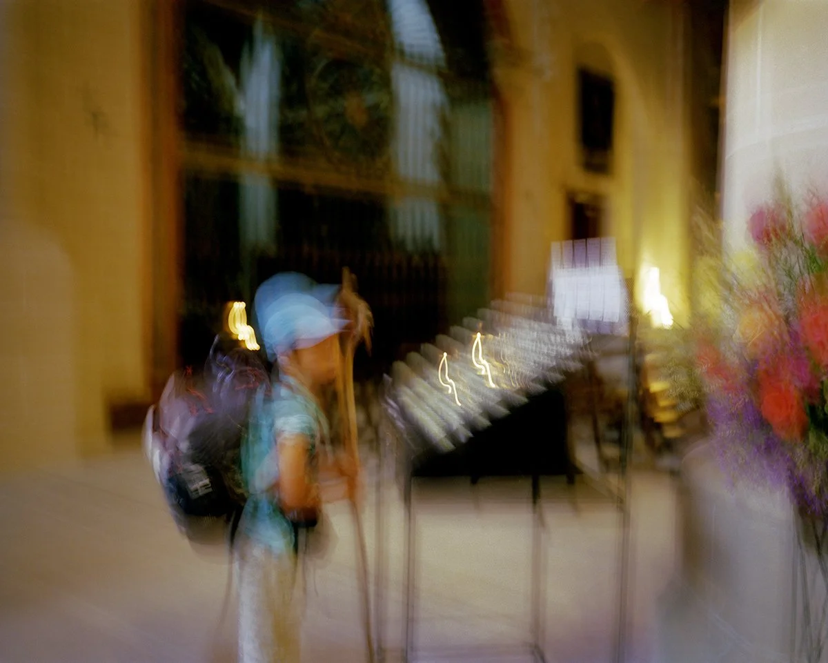 A person wearing a backpack and a blue hat, in an indoor environment, with an artistic blur and lights.