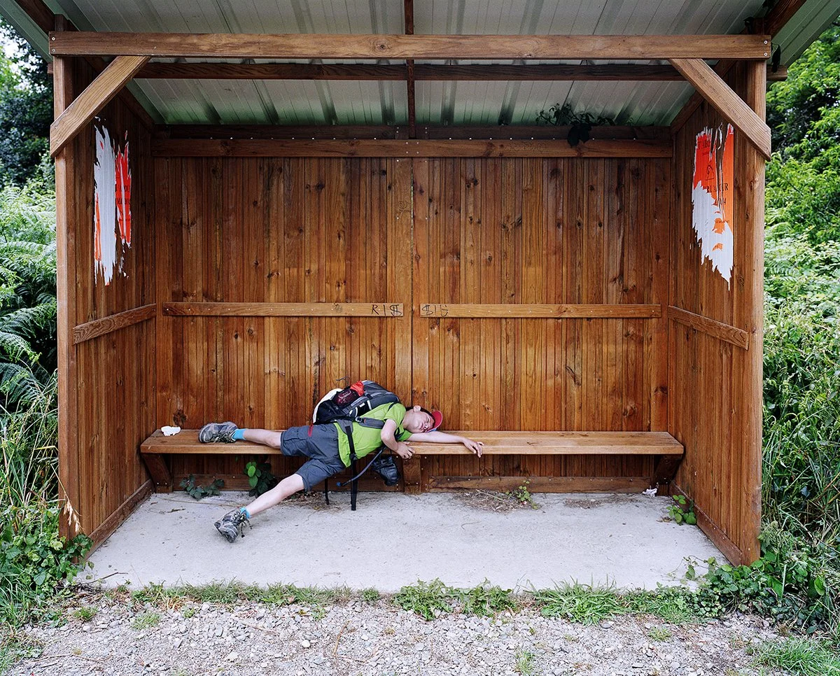 A child asleep in a wooden bus stop in the countryside