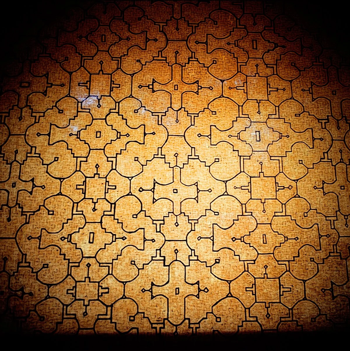 A labyrinth in the form of a geometric mosaic in shades of brown and black.