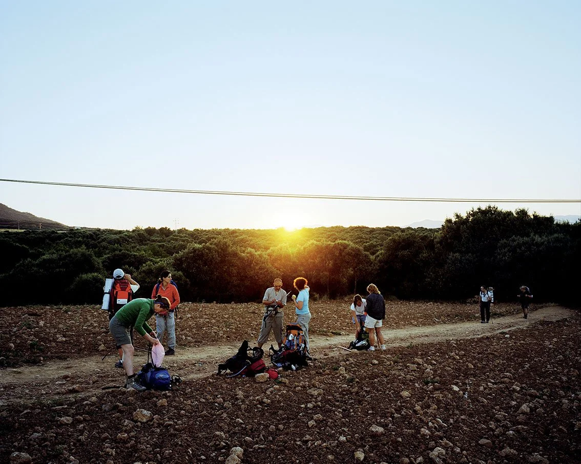 Group of people hiking at sunset in a mountain landscape, with backpacks and hiking clothes.