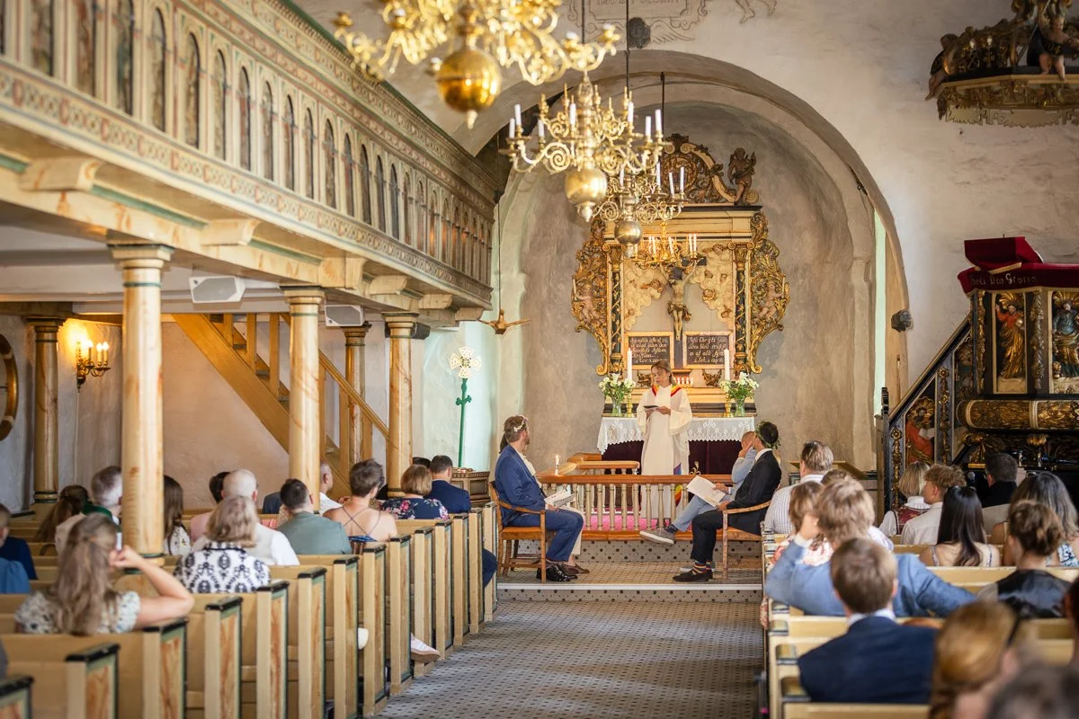 En gruppe mennesker i en kirke med en prest som holder en tale foran alteret.