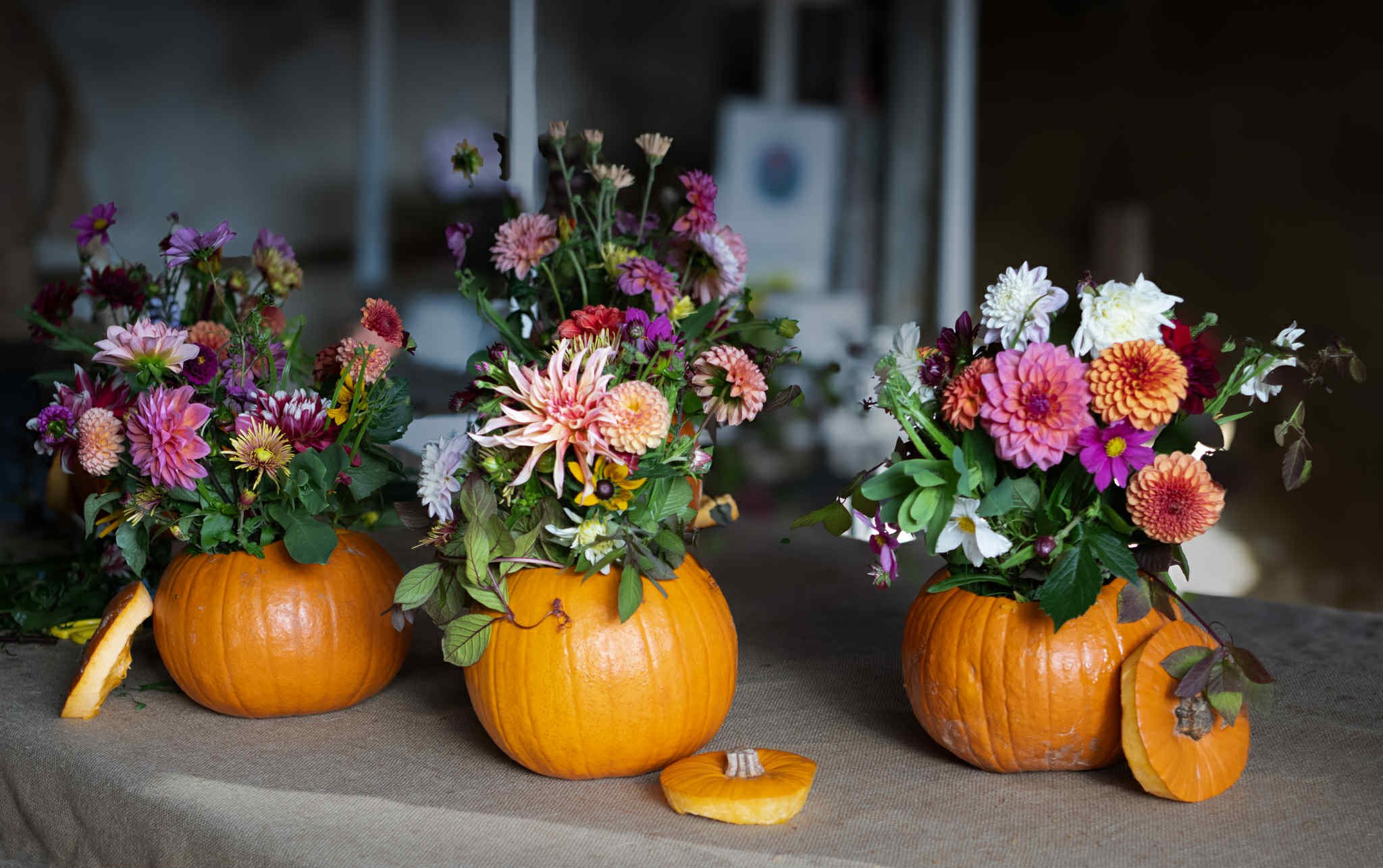 Pumpkins with colorful flower arrangements in them on a table.