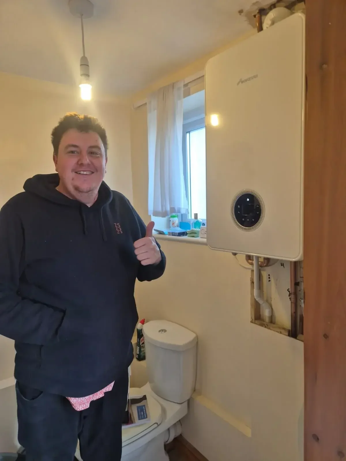 Man in front of new boiler with thumbs up