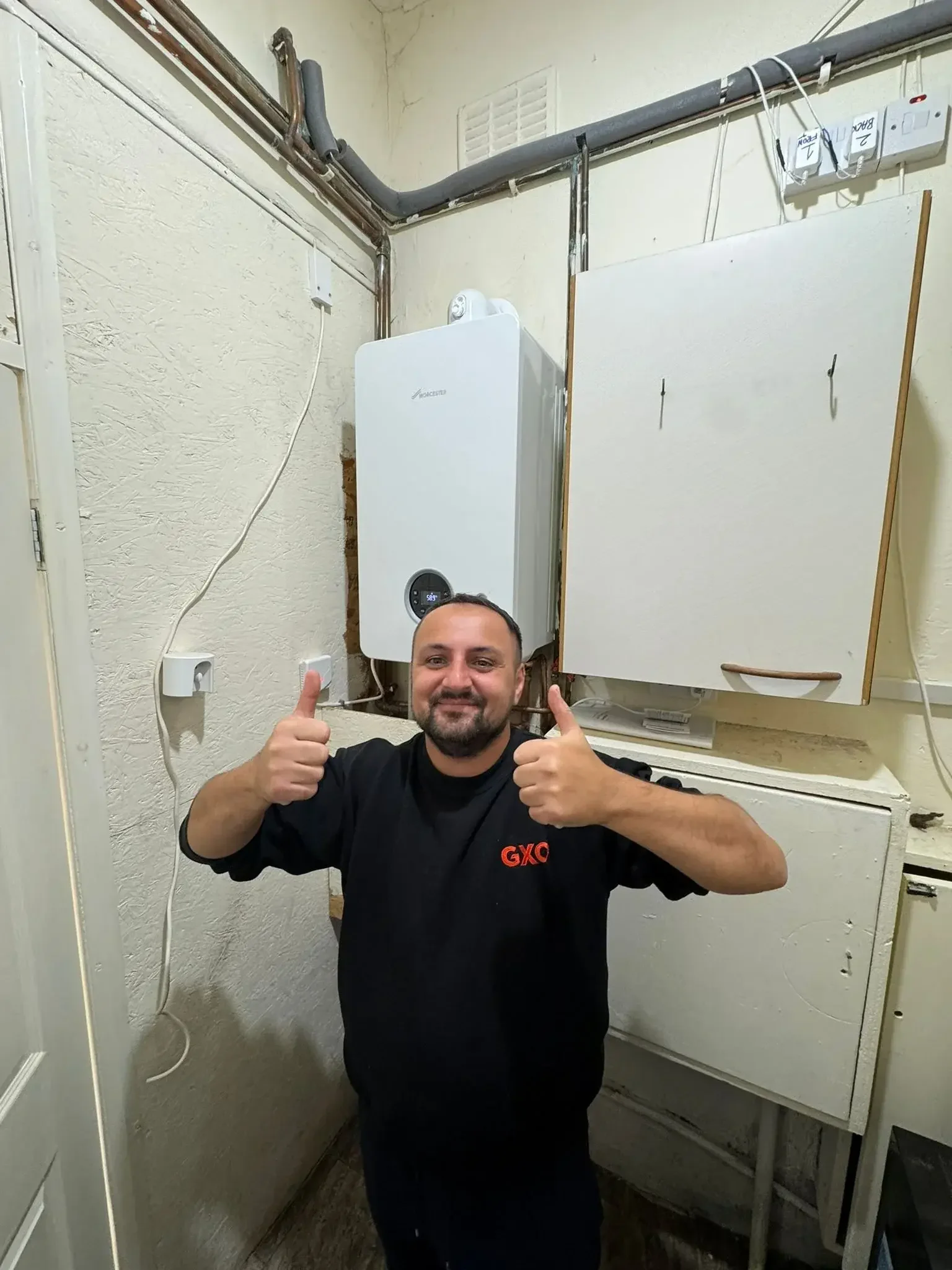 Happy customer with thumbs up in front of boiler