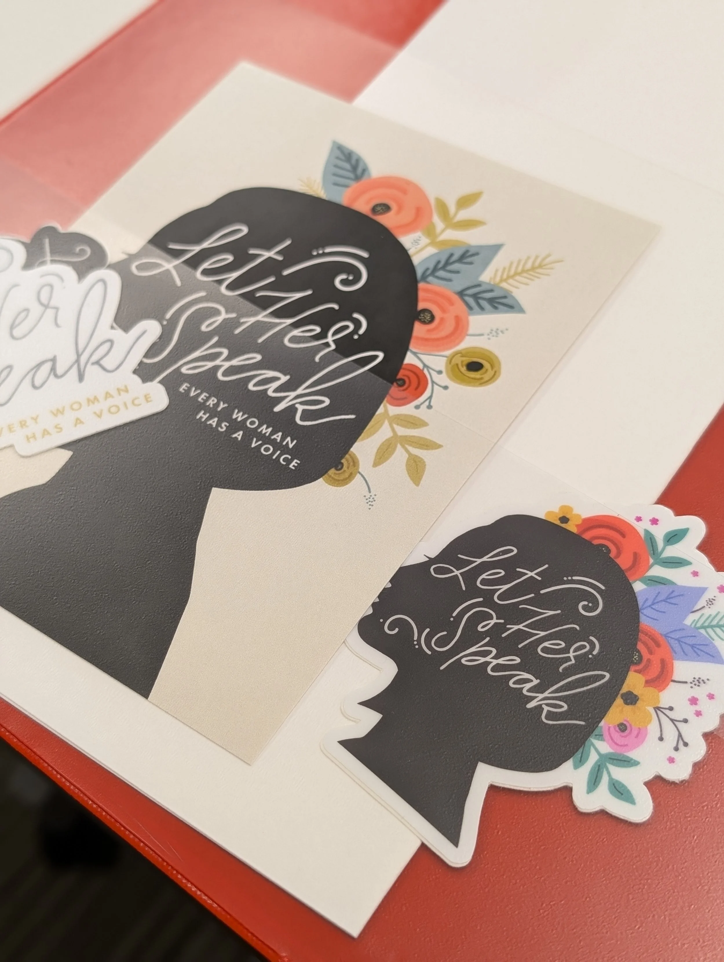 Red binder with "Let her speak" stickers in the pockets