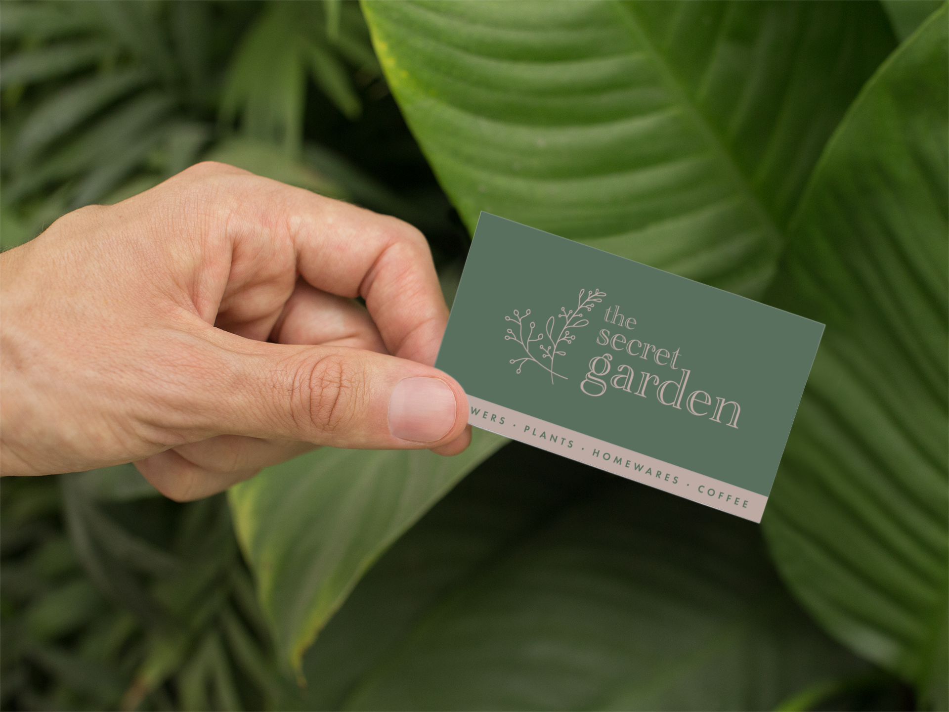 mockup-of-a-man-holding-a-business-card-by-some-palm-leaves-33838.png