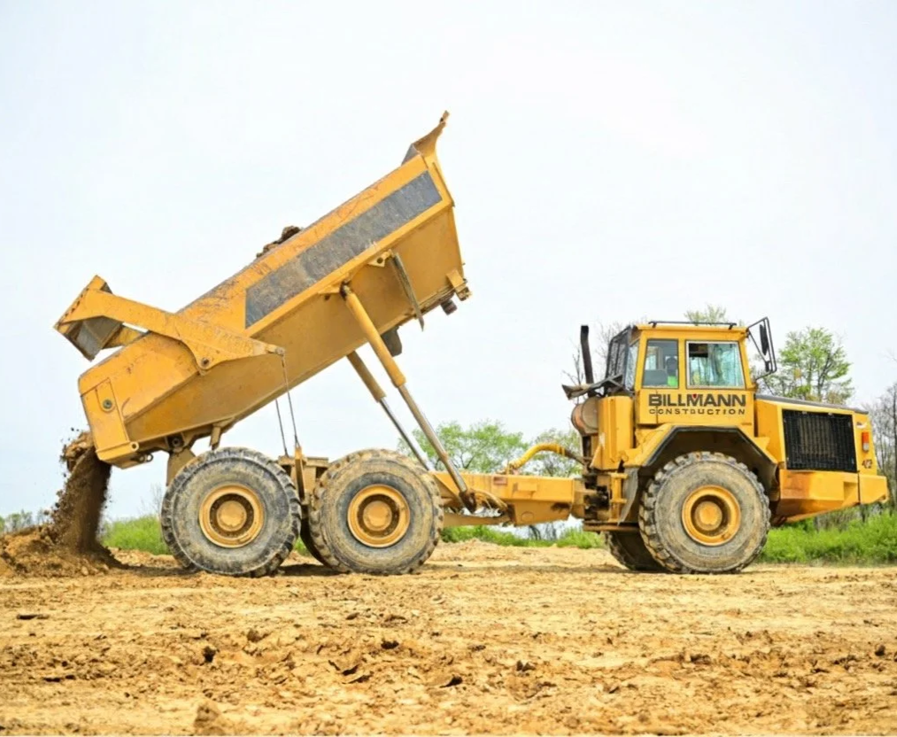 Inside a modern dairy farm barn with Holstein cows lying down in designated feeding areas under a metal and glass roof.