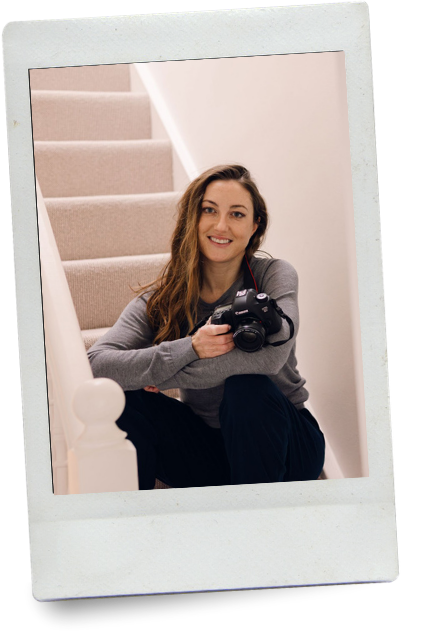 A woman sitting on a staircase holding a camera and smiling