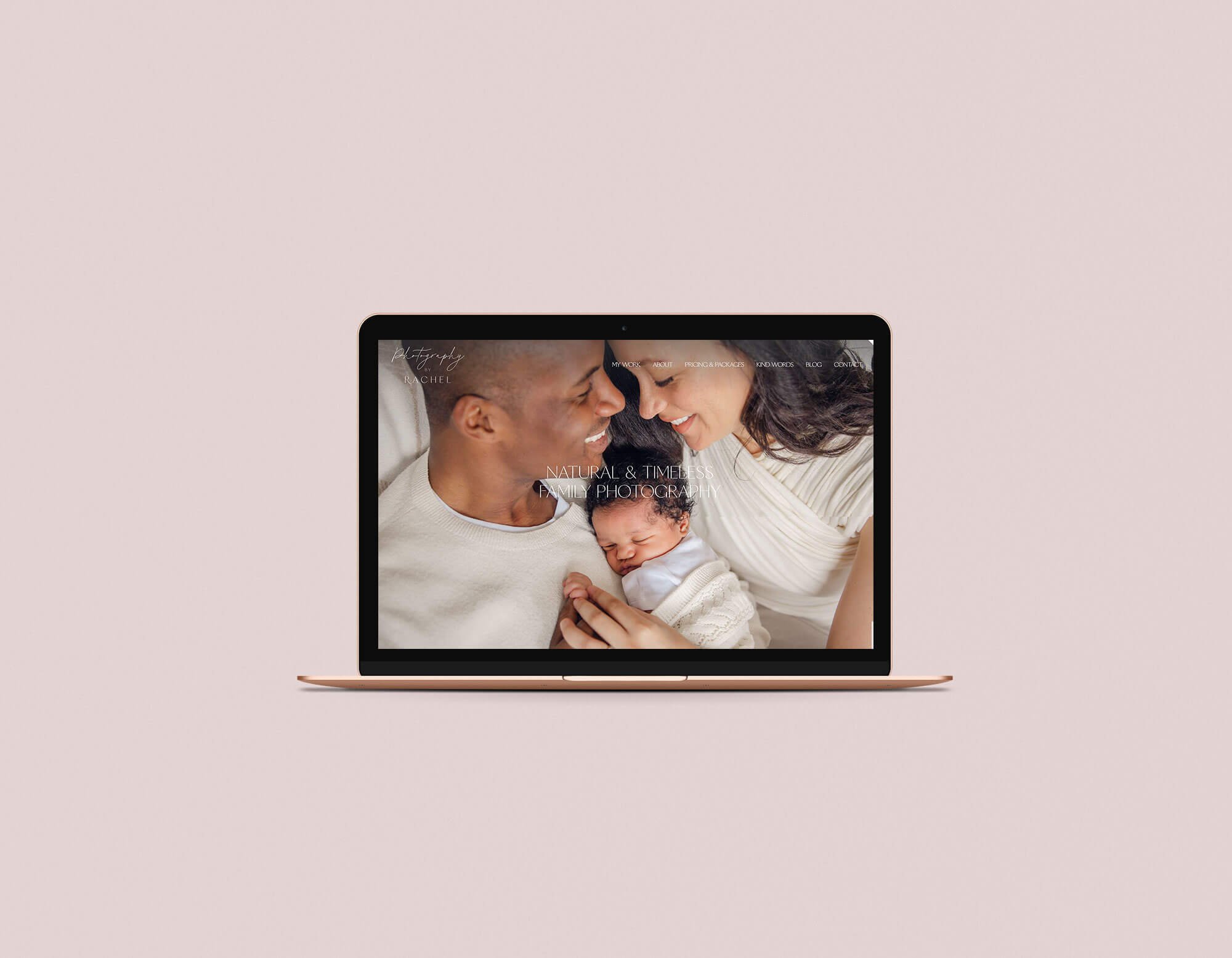 Laptop displaying a family photograph of two adults and a newborn baby with a pink background.