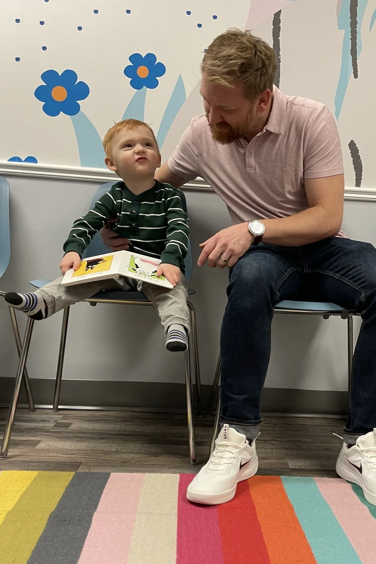 Young boy with father on two chairs in waiting room, preparing for a screening at Elemenoe in Waterloo