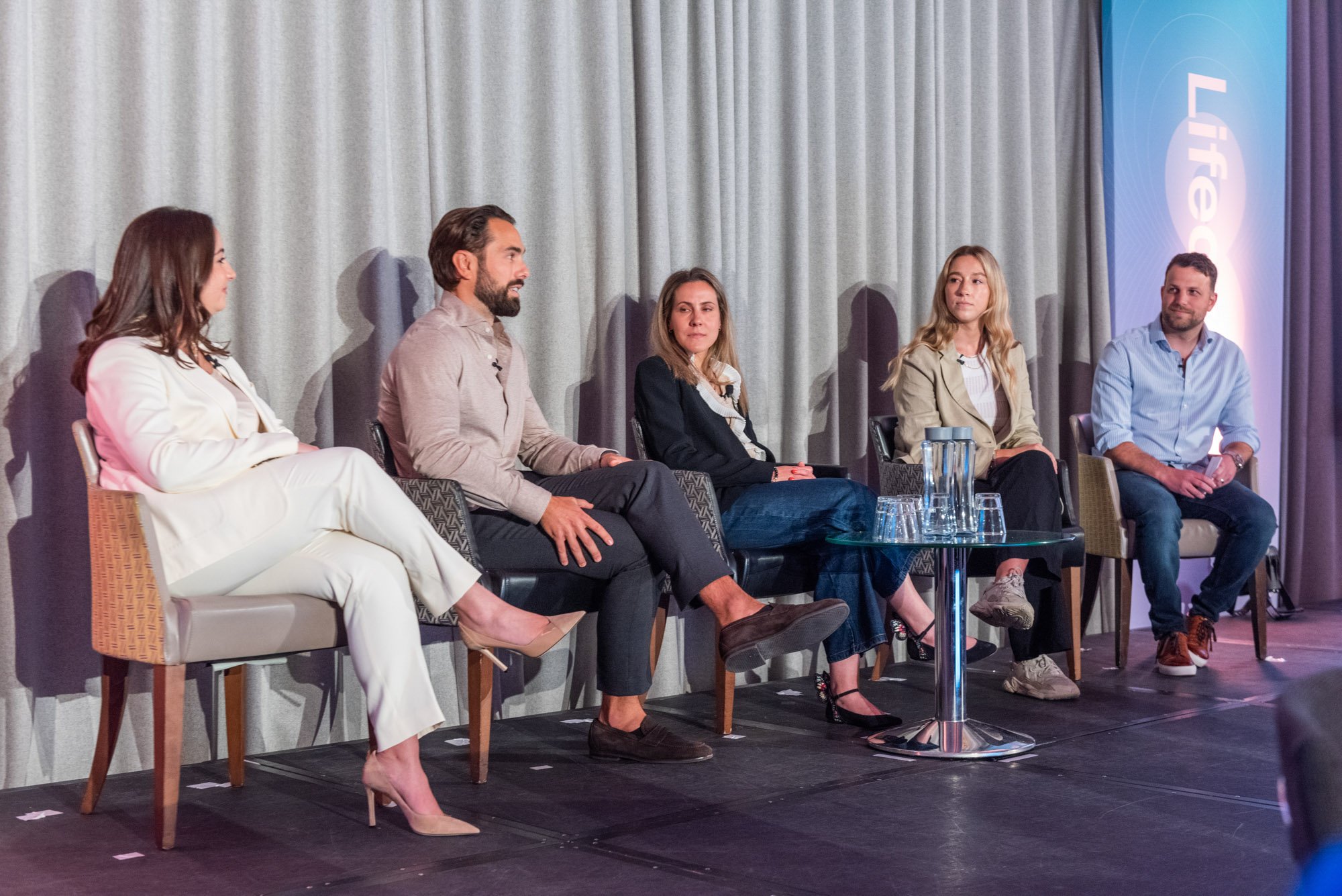  A diverse group of individuals sitting on chairs at a conference, engaged in discussions and sharing ideas. 