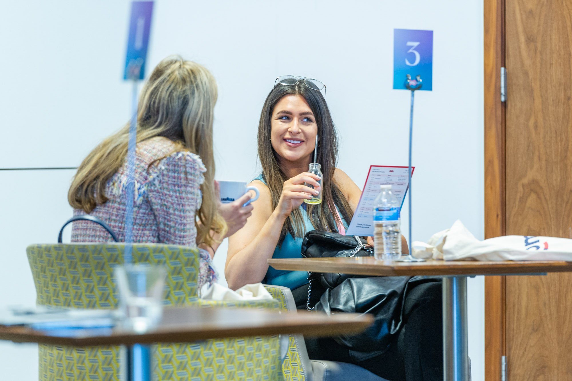  Two women enjoying a drink together at a table, sharing laughter and conversation. 