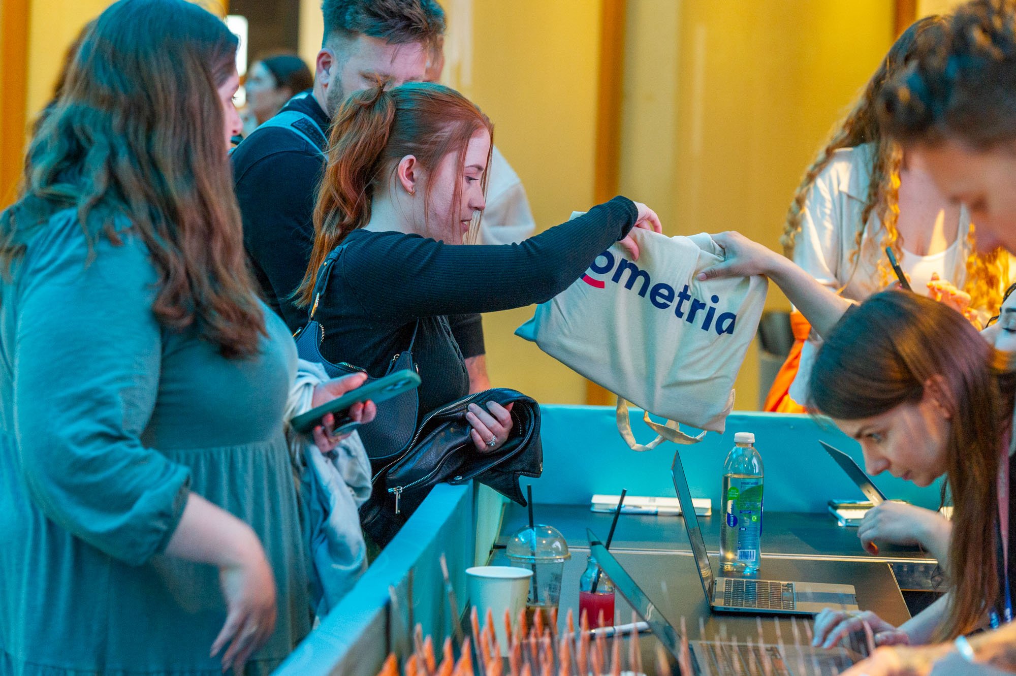  Excited individuals surrounding a table, curious about the contents of a bag filled with freebies. 