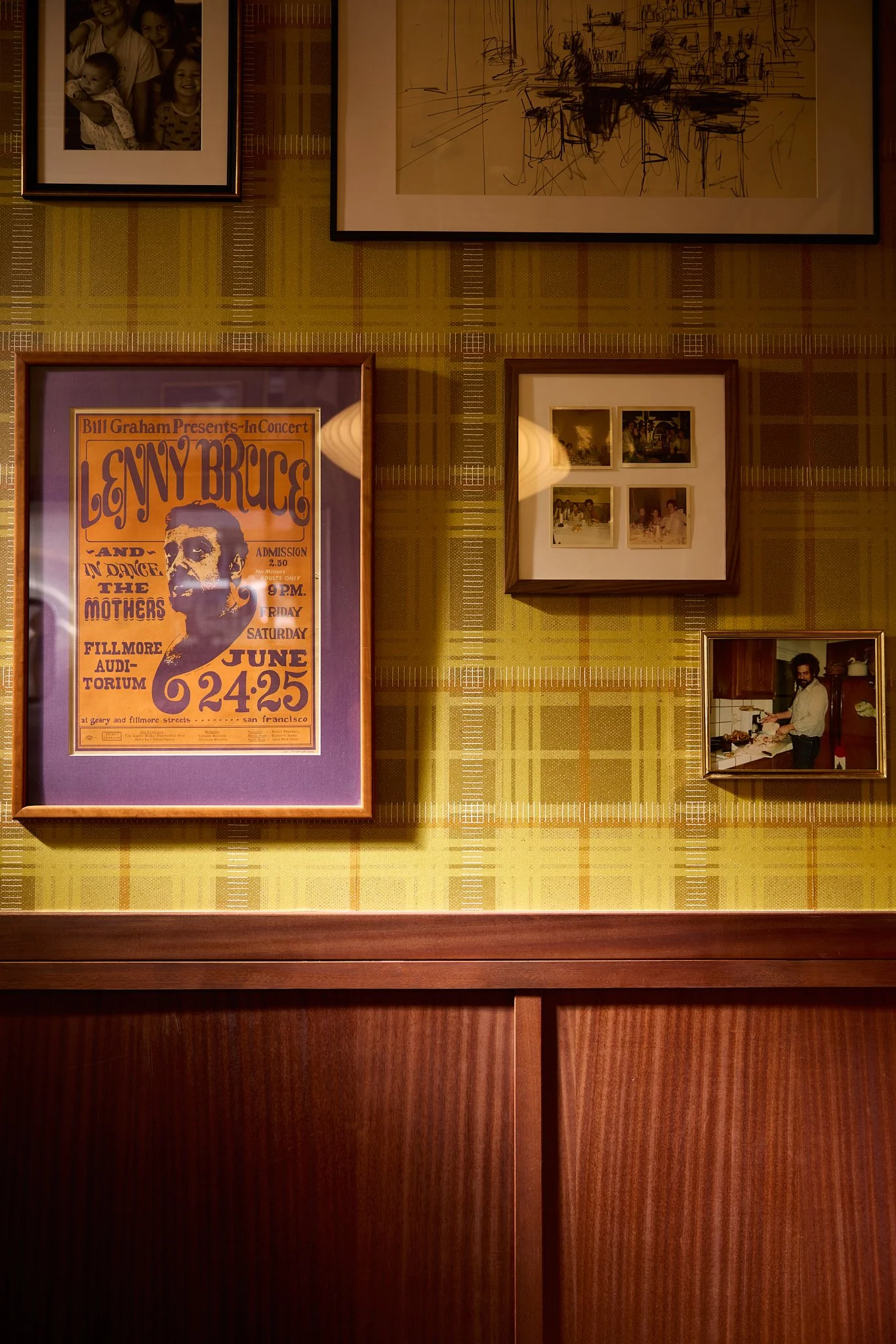 Close-up of wood wall paneling, wallpaper and gallery wall of vintage art and family photos in an Encinitas hospitality project. 