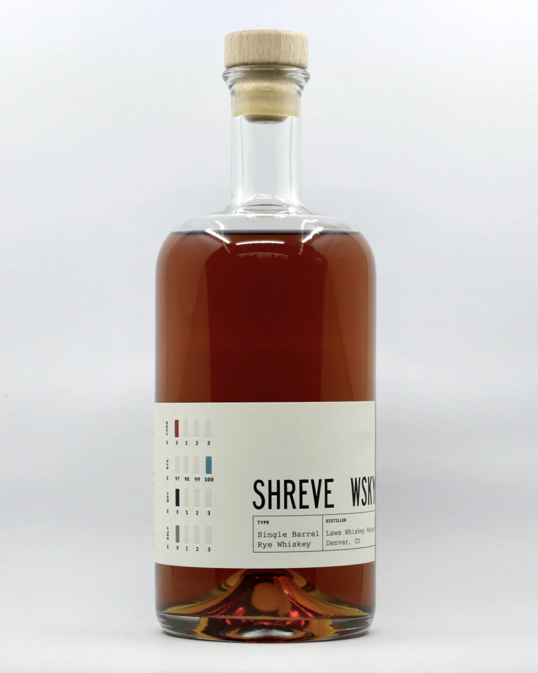 A clear glass bottle of whiskey with a light wood cap, filled with amber-colored whiskey, featuring a white cream-colored label with black text and colored boxes.