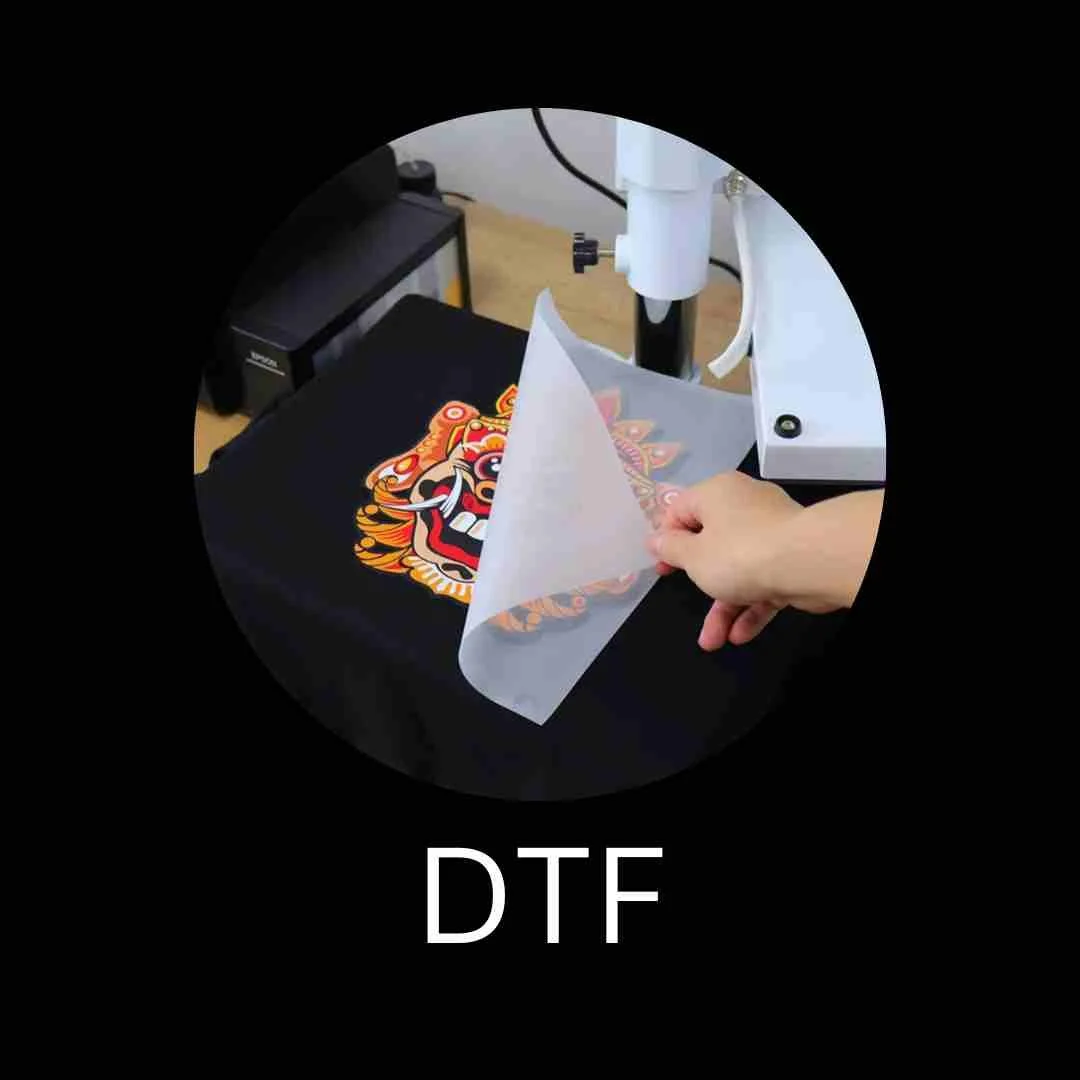 A person peeling transfer paper off a colorful tiger design on a black surface, with a microscope in the background and the text 'DTF' at the bottom.