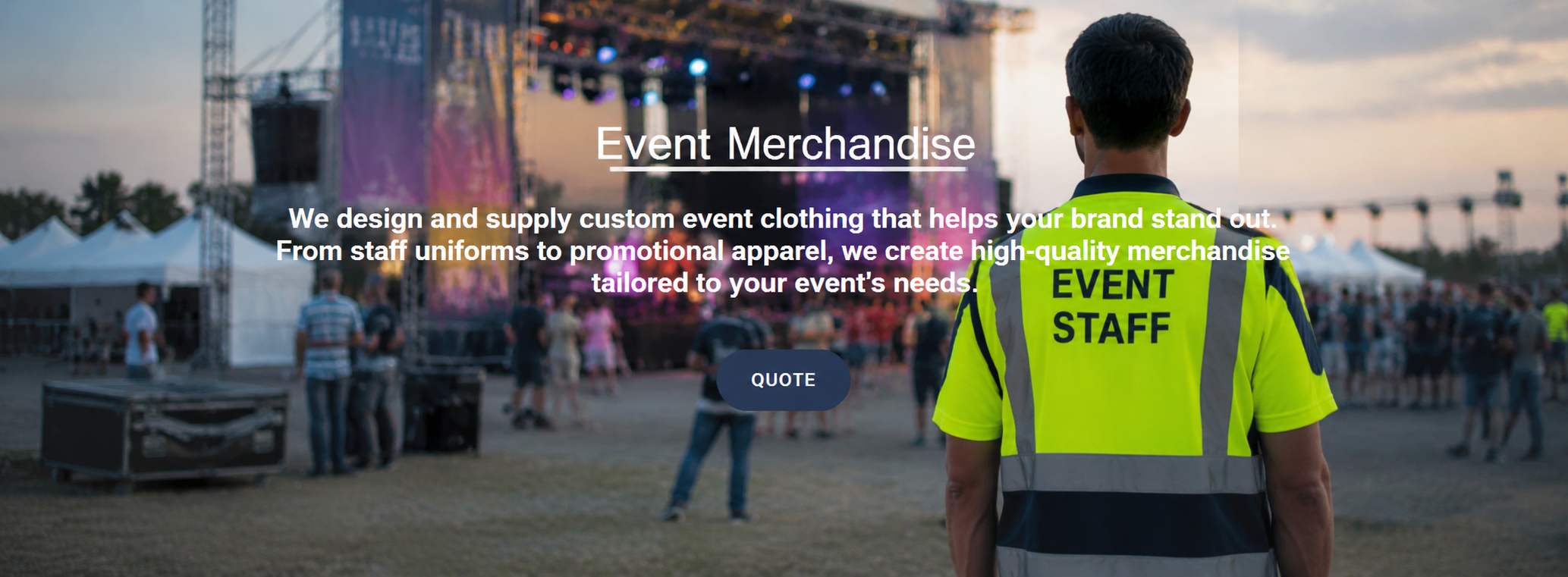 A man wearing a bright yellow "Event Staff" vest standing in front of a stage at an outdoor event during sunset.