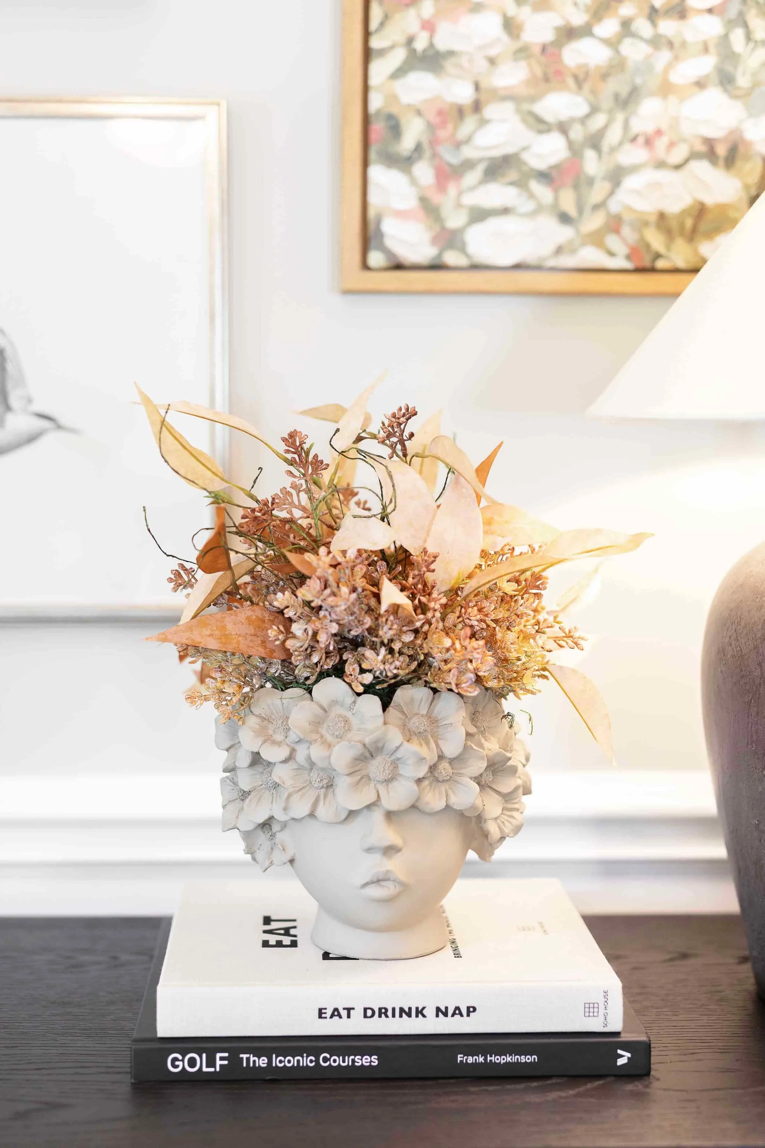 Female bust with faux flowers on top of stack of books