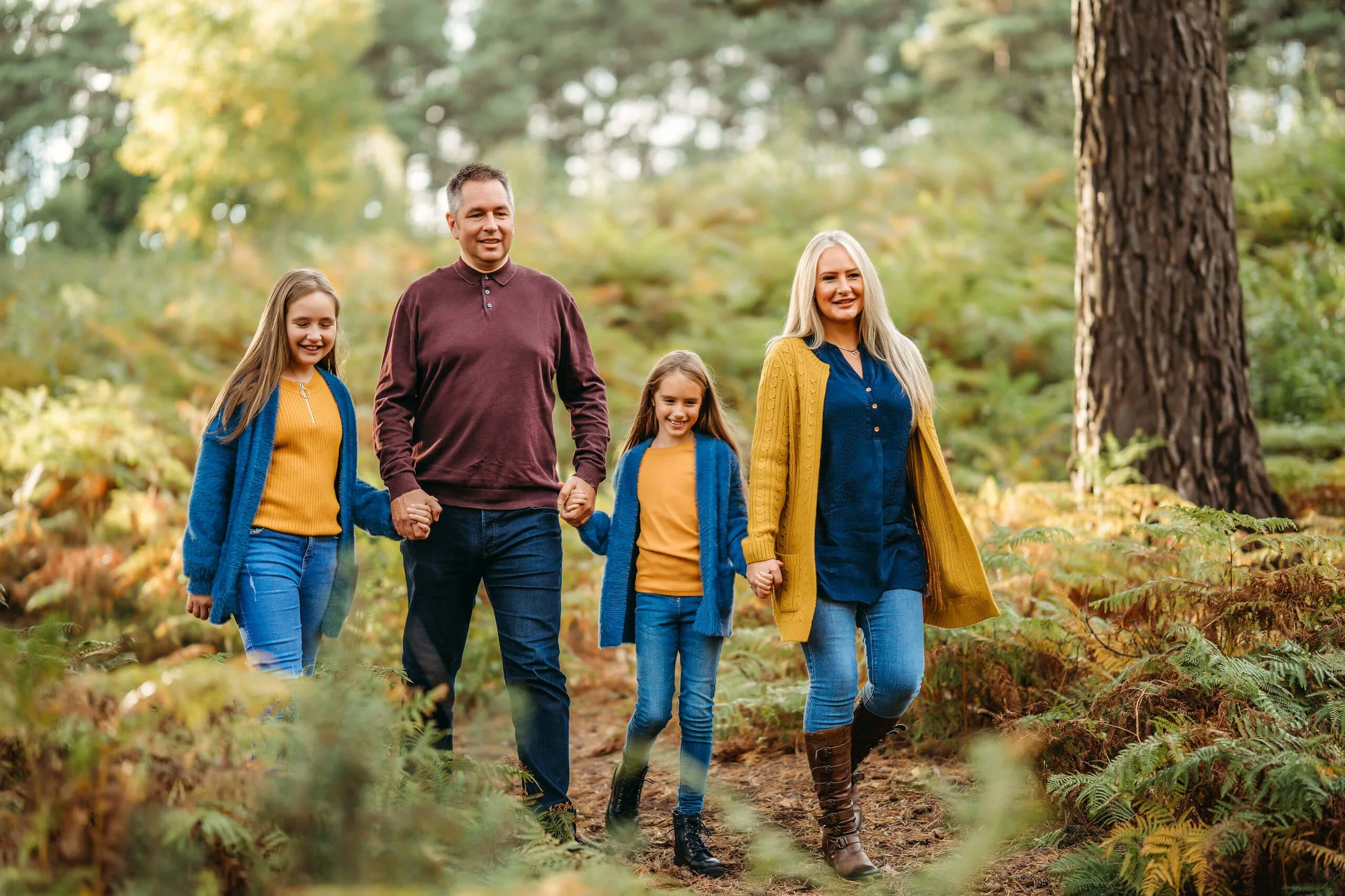 Colourful autumn family photo of a family with two daughters holding hands together taken by family photographer in Guildford. Family photography in Woking, Shere, Aldershot.