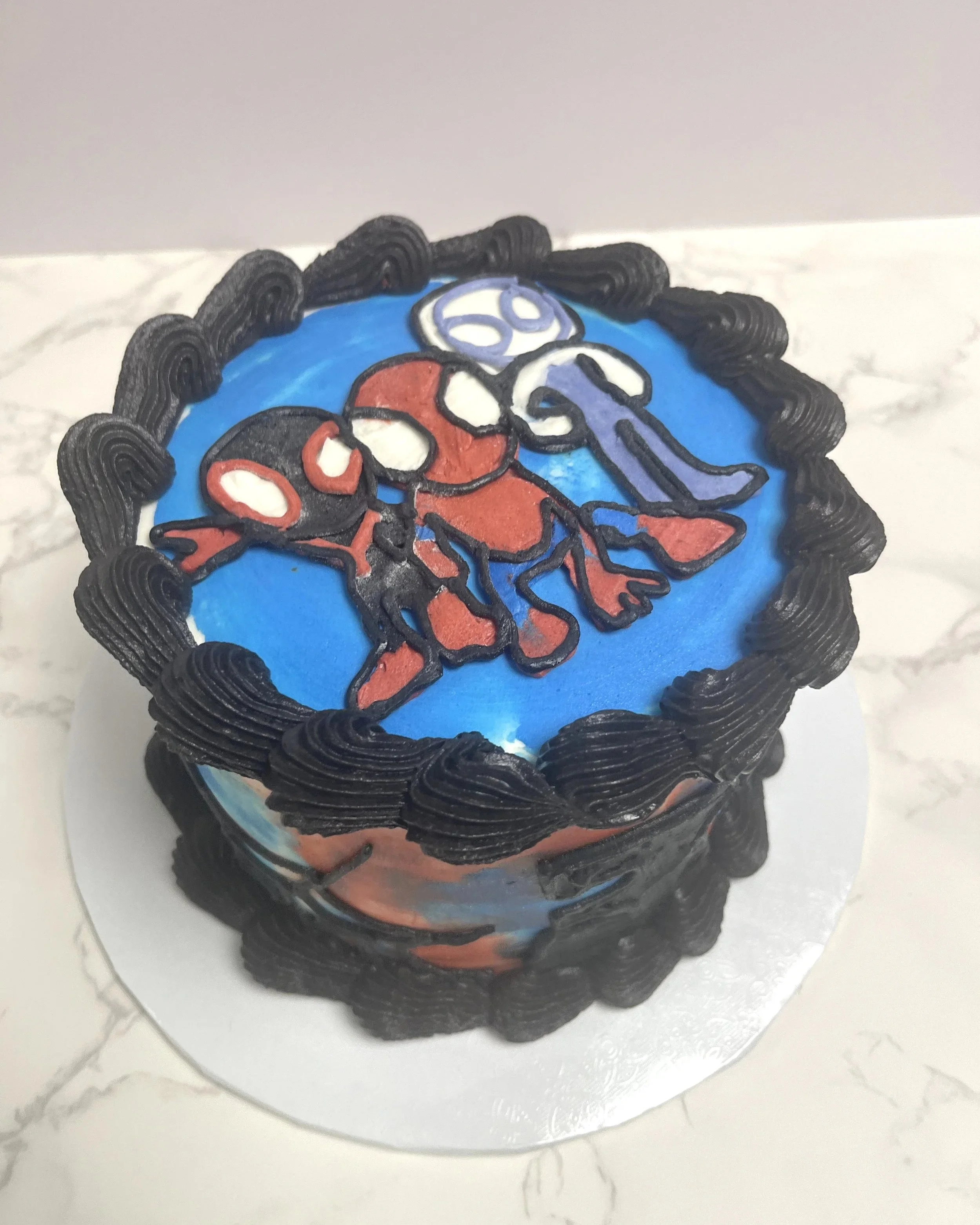 A Spider-Man themed birthday cake with black frosting border and a Spider-Man character design on top.