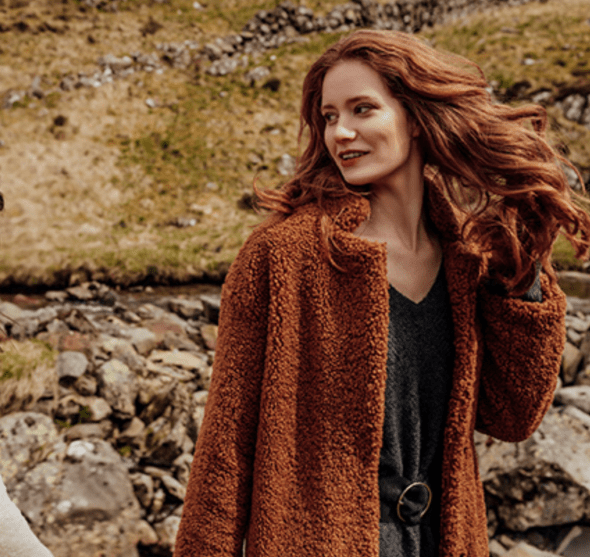 Model with long red wavy hair wears rust coloured borg jacket