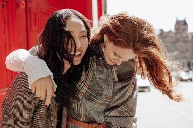 two models laugh together wearing plaid jackets