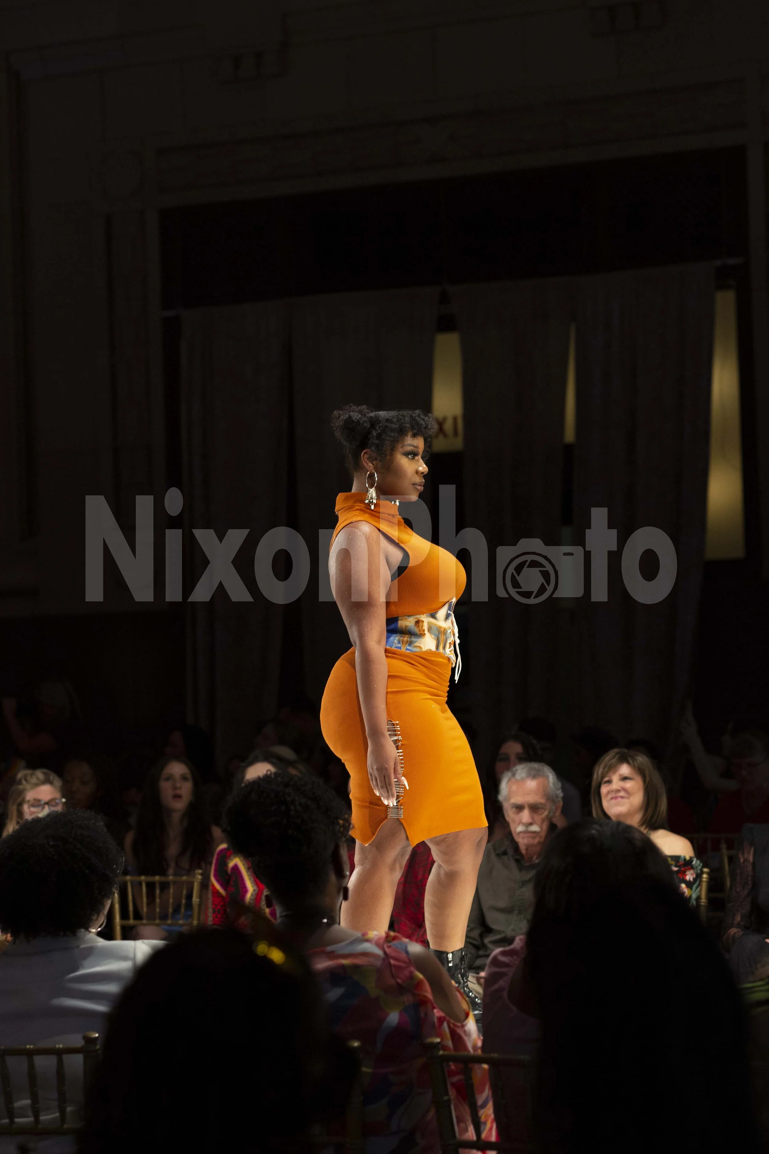 Model in orange dress on runway during fashion show