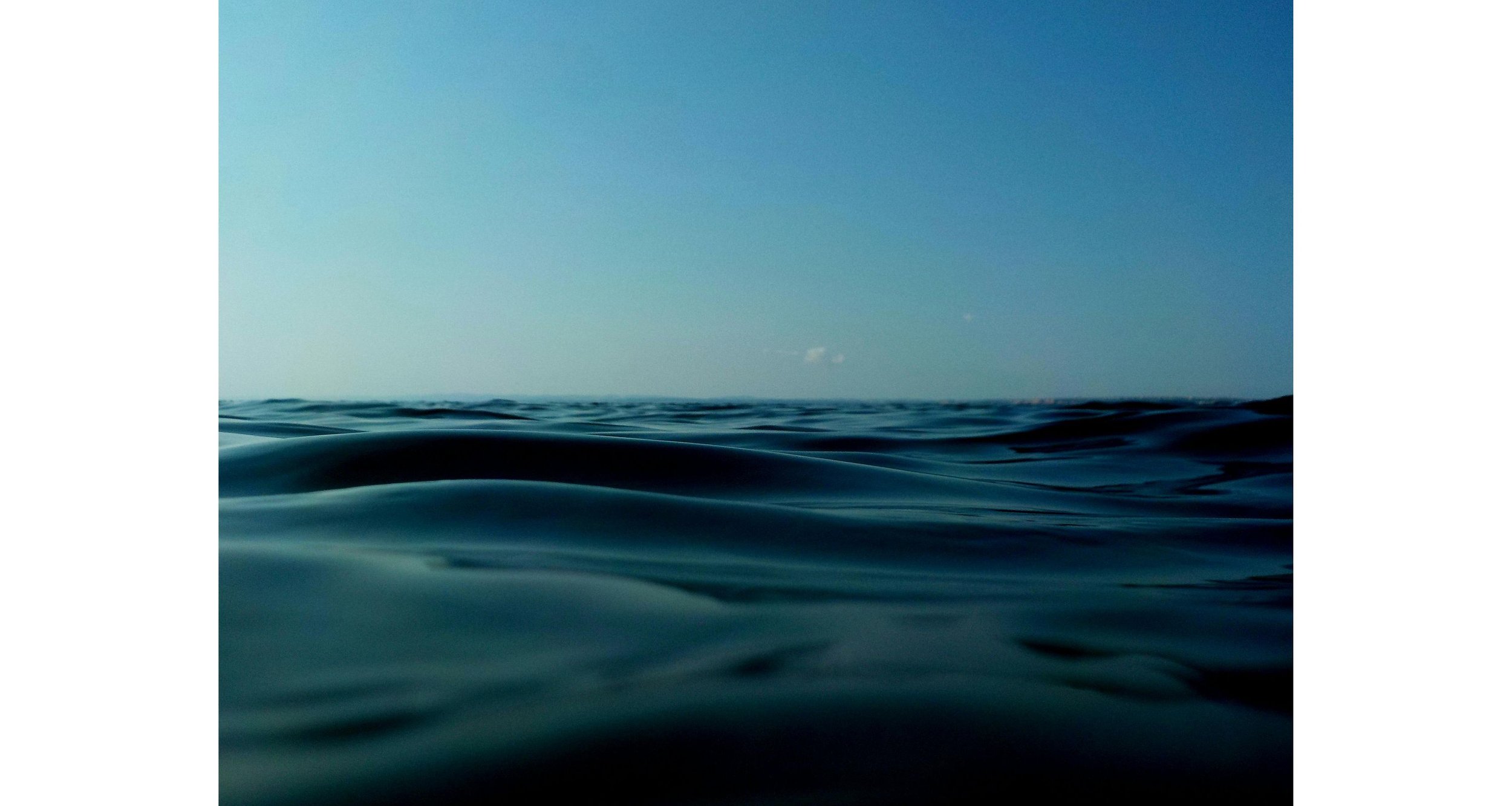 Ocean water with gentle waves under a clear blue sky.