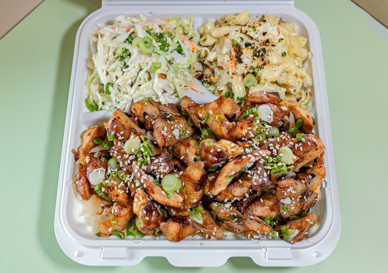 Single item plate of teriyaki chicken served over white rice with sides of house slaw and macaroni salad.