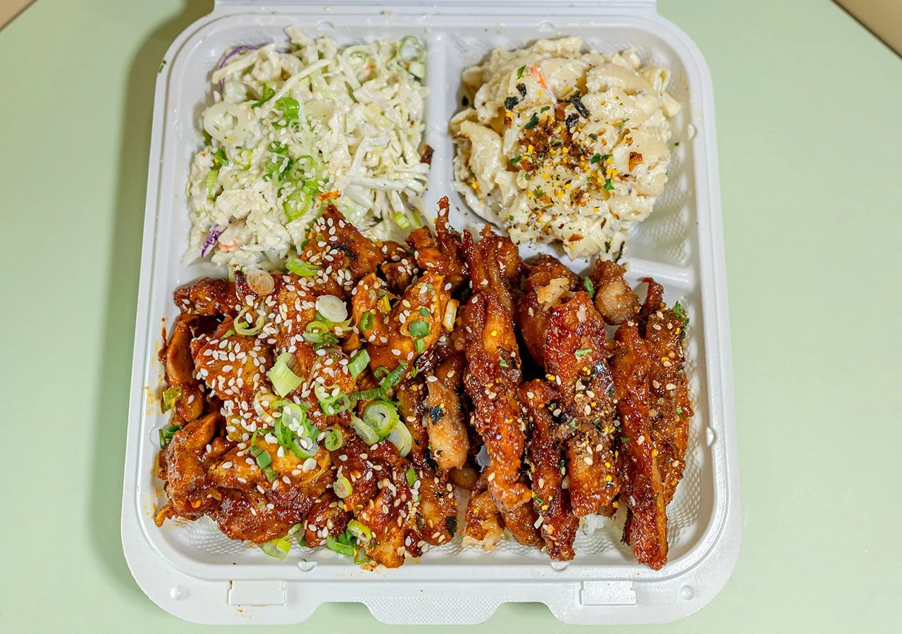 Two chicken protein combination plate over rice with side of house slaw and macaroni salad.