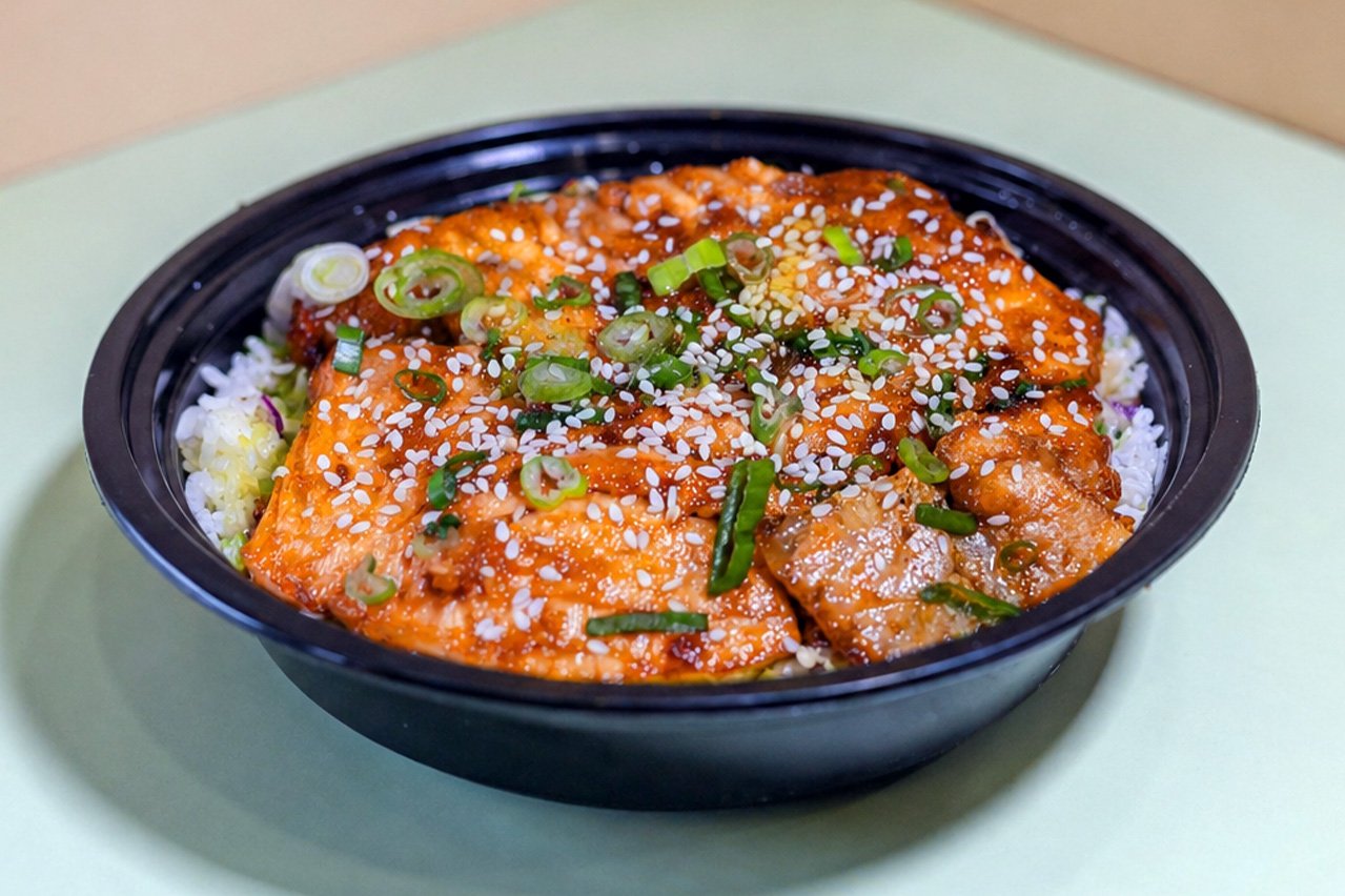 Salmon filet coated in a savory-sweet glaze made from soy sauce, honey, and garlic, served with two scoops of white rice.