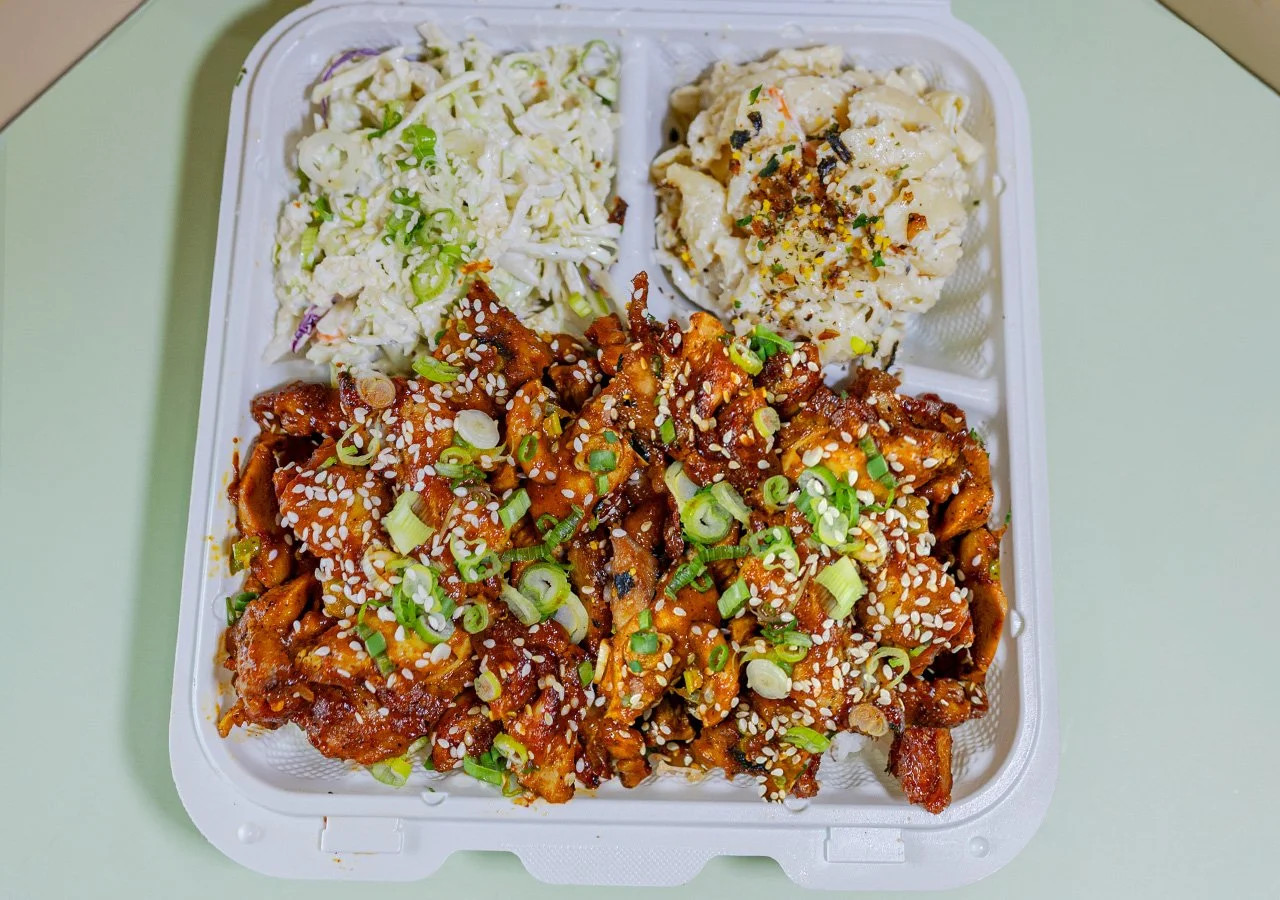 Single item plate Barbeque chicken served over white rice with sides of house slaw and macaroni salad.