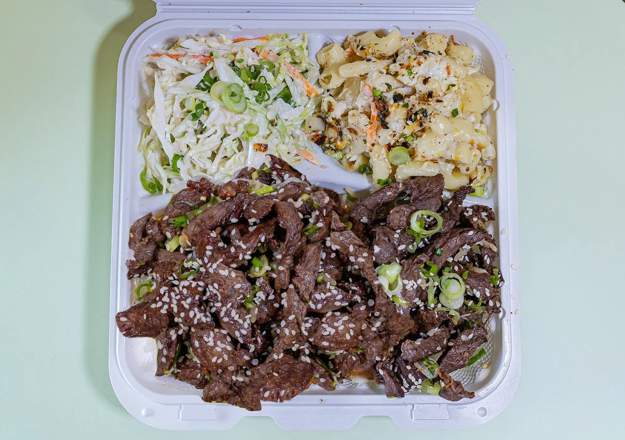 Single item plate of Beef Skirt Steak Glazed with teriyaki sauce served over white rice with sides of house slaw and macaroni salad.