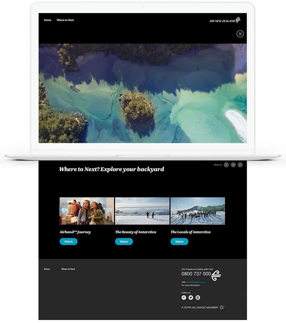 Laptop screen displaying Air New Zealand website with aerial view of a river or lake and surrounding greenery at the top, and travel options including Antarctica exploration at the bottom.