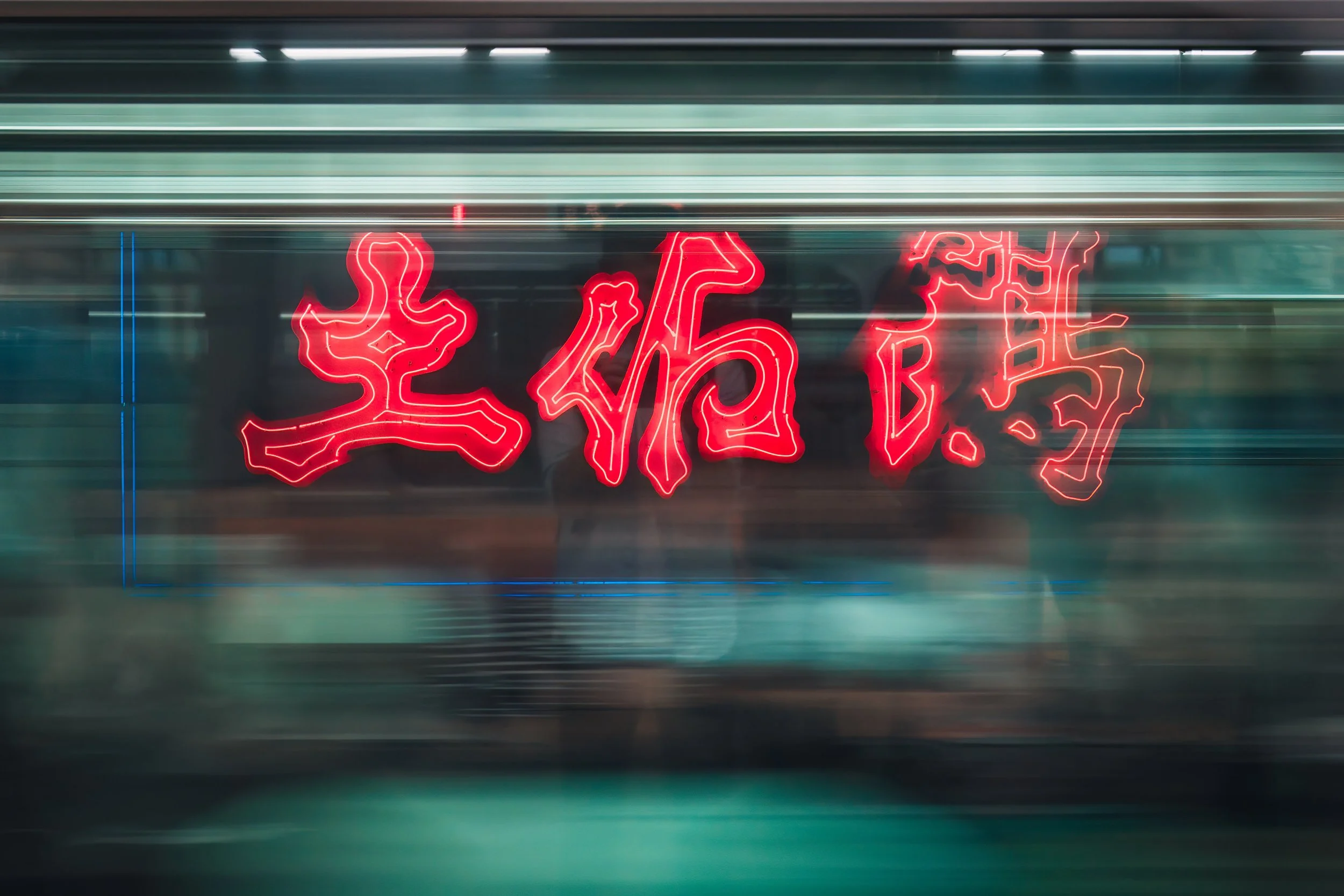 Red neon Kanji sign at Tokyo’s Kanda Station seen through a speeding train window at night