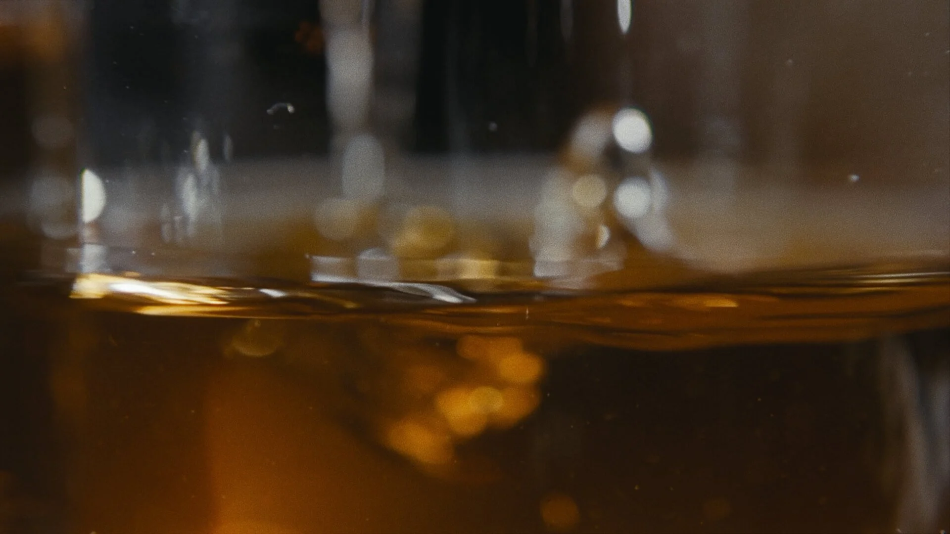 Close-up of droplets of a dark-colored beverage on a glass surface.