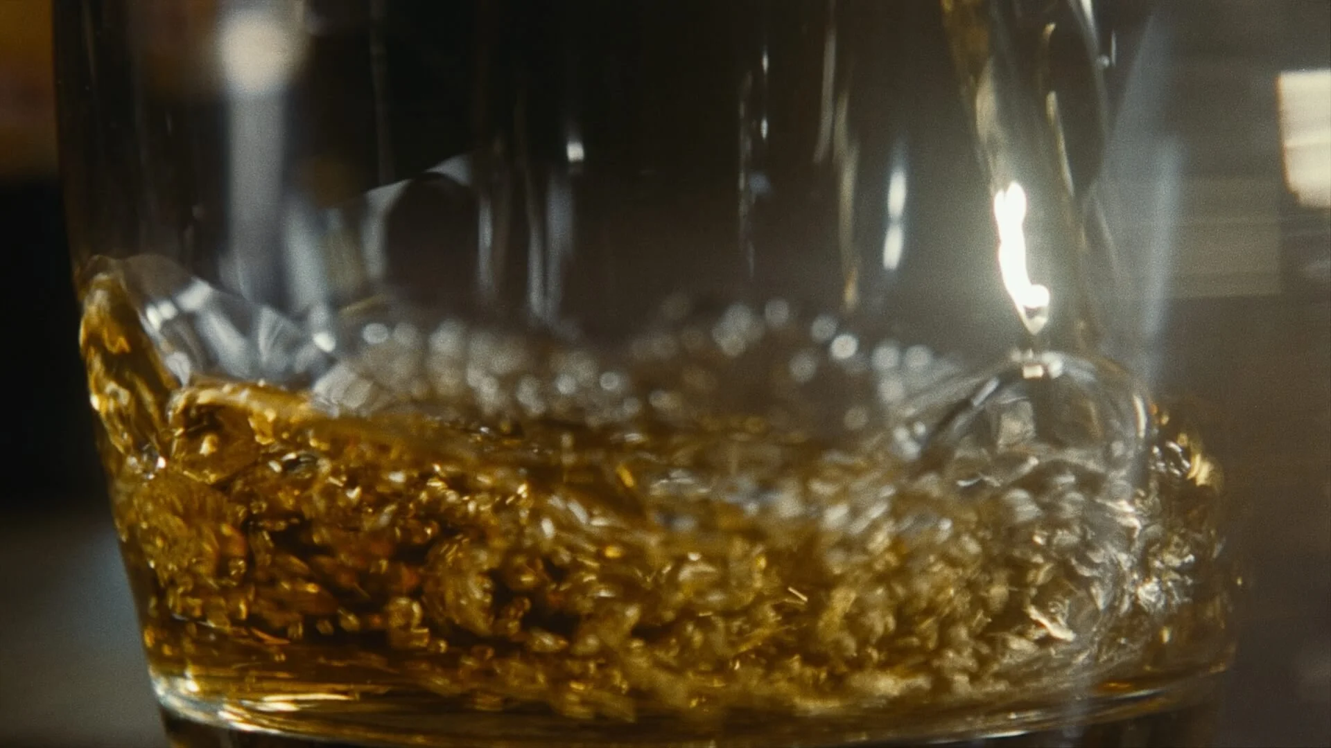 Close-up of a glass with a dark beverage and ice cubes inside.