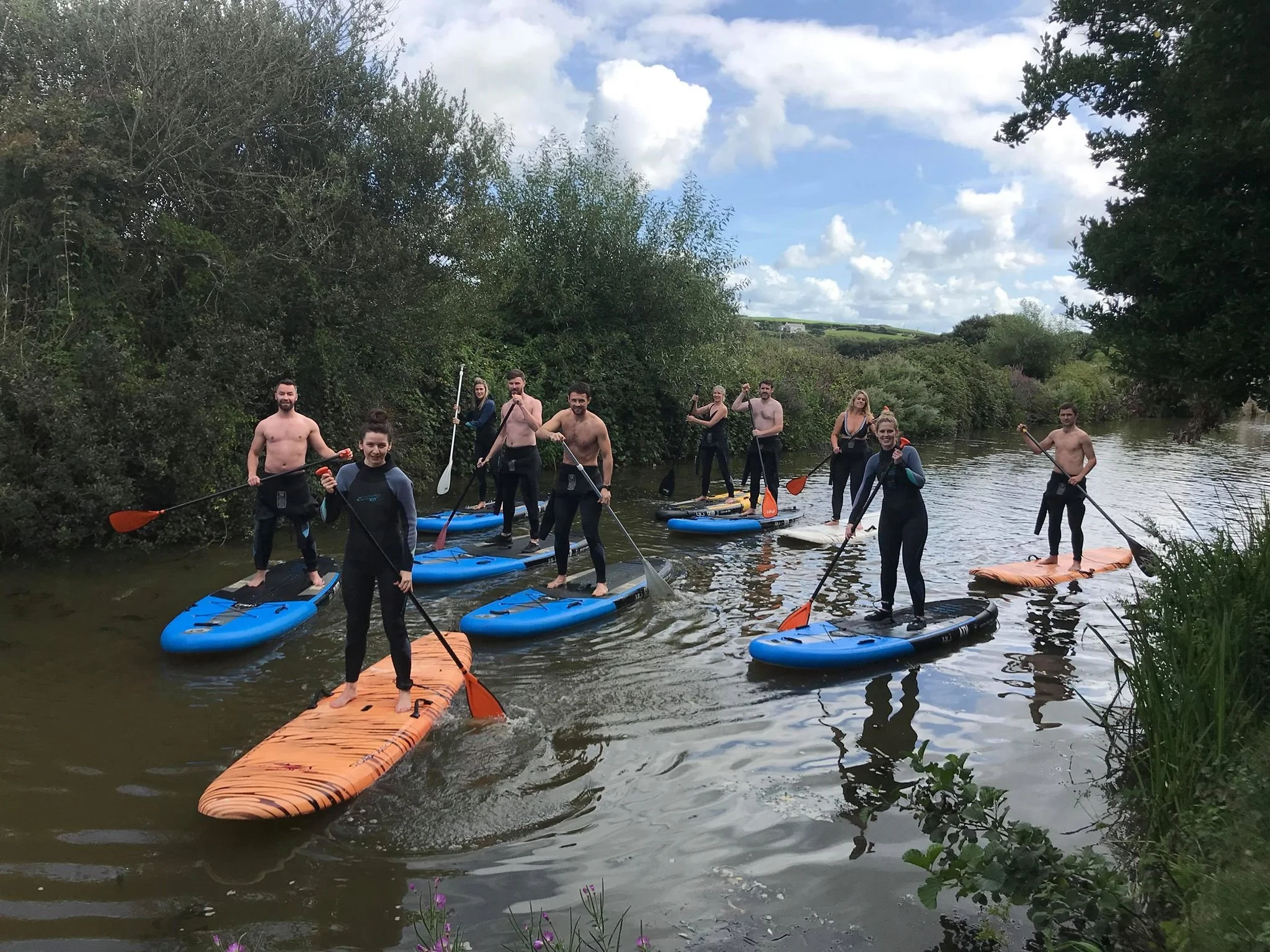 Group enjoying stand-up paddleboarding on calm water in Bude