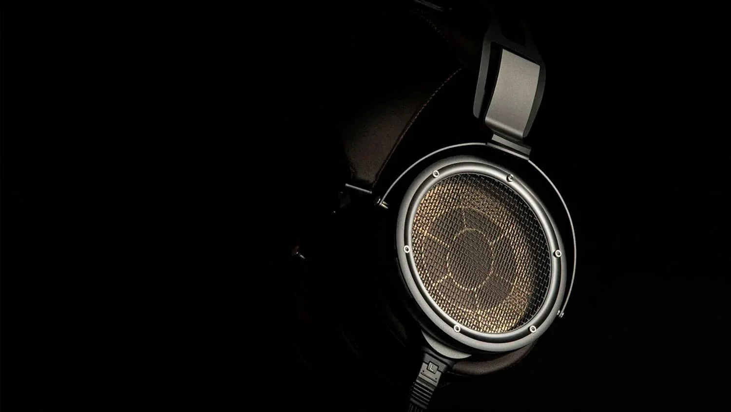 Close-up of a STAX Electrostatic SR-9000 headphone with copper speaker grill, set against a dark background.