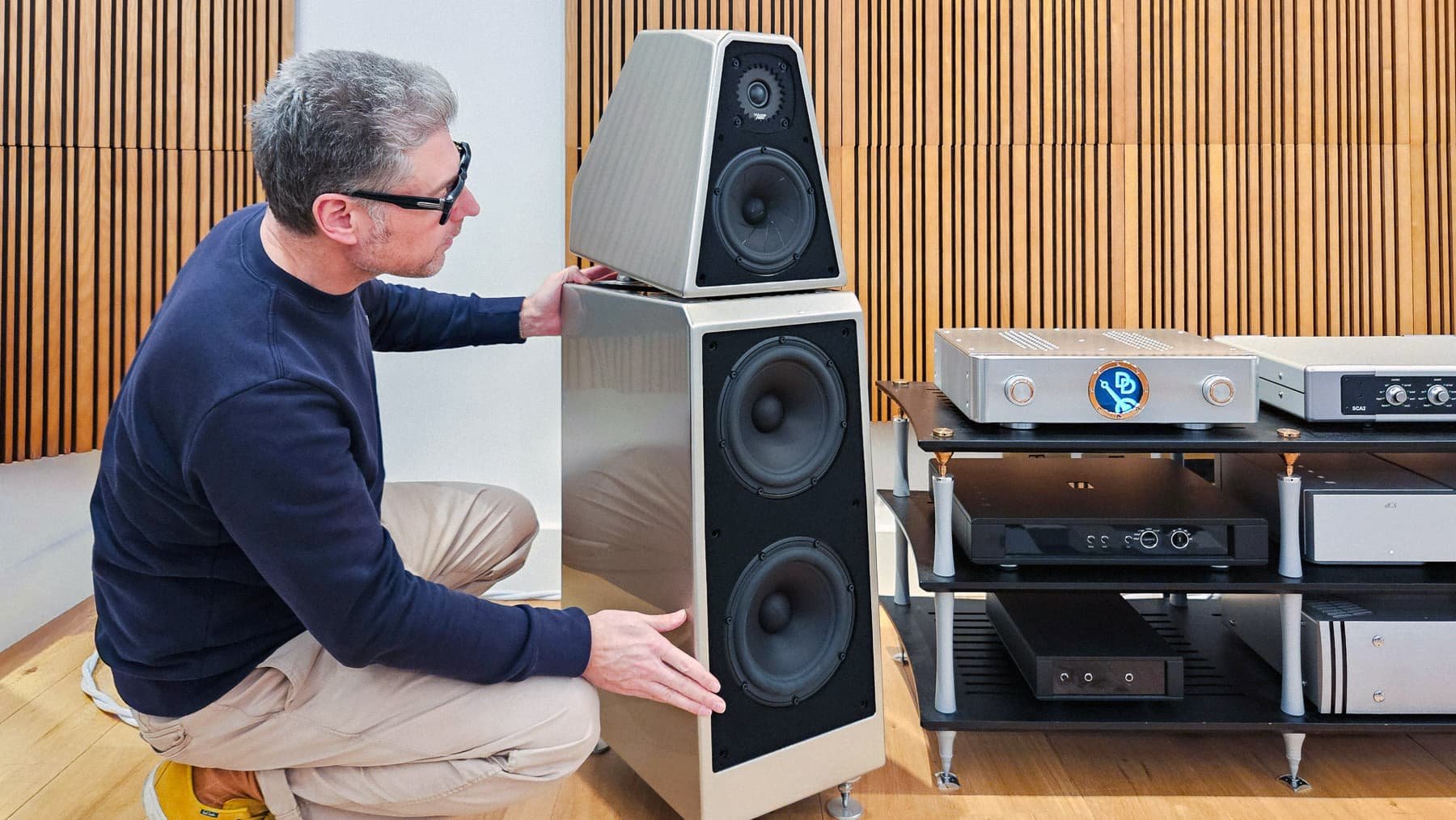 Dean adjusting a Wilson WATT/Puppy speaker in Quartz in our listening room with wooden acoustic wall panels.